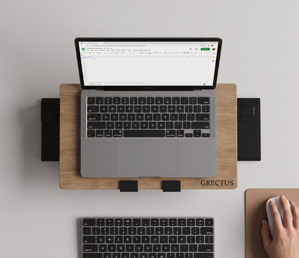 Vista de cima de uma mesa: o ARDEA eleva um notebook à altura dos olhos, com teclado e mouse à frente.